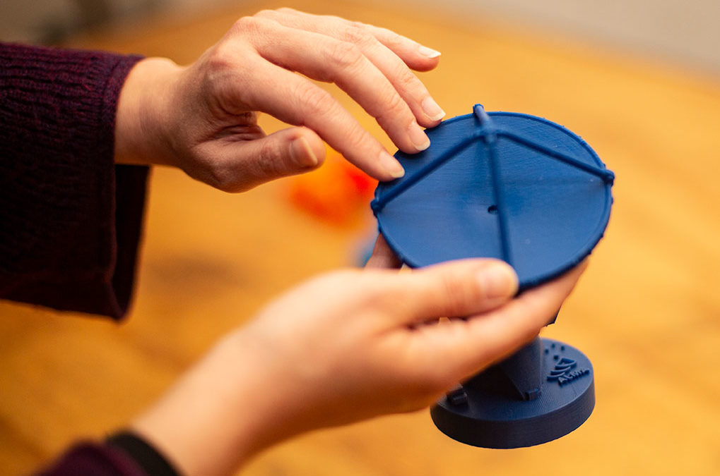 Hands touching a miniature model of an ALMA satellite